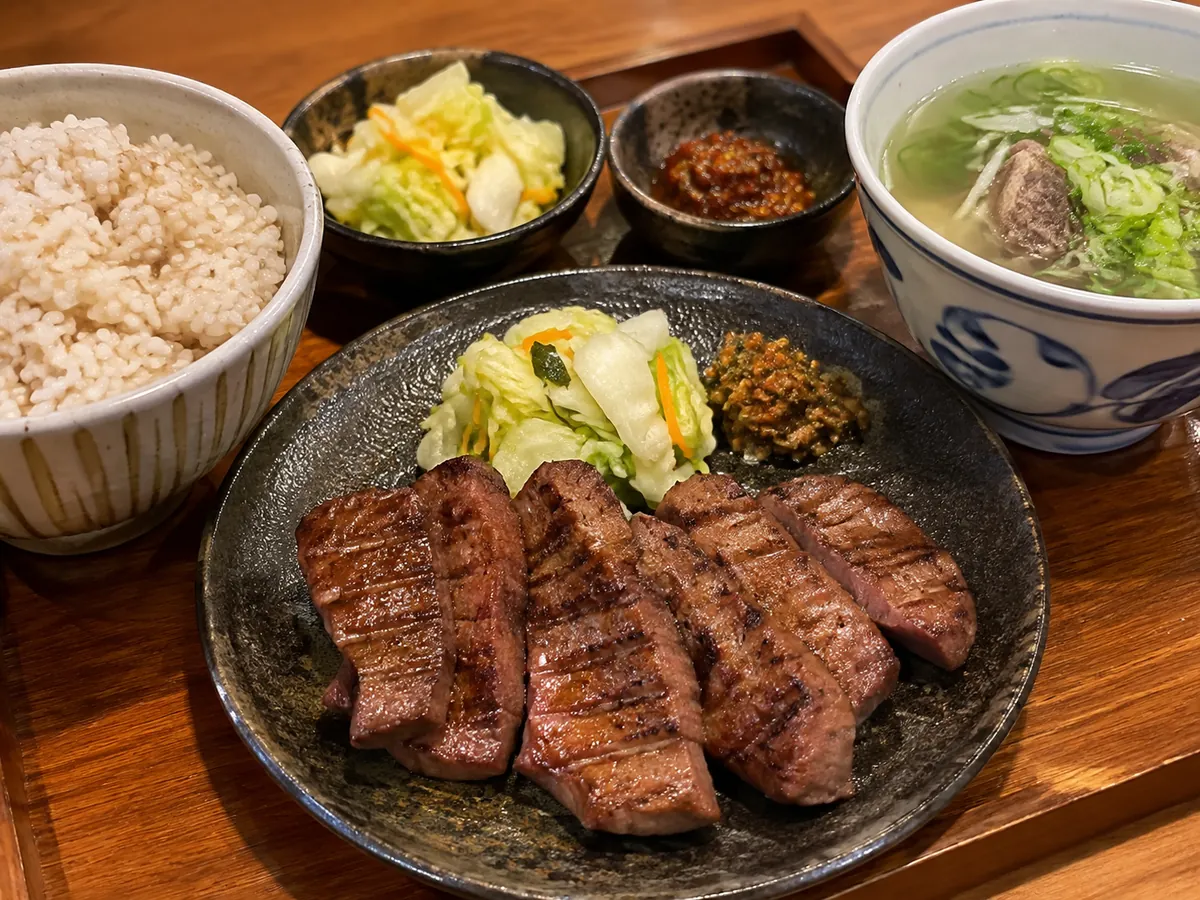A gyutan set meal with grilled beef tongue, barley rice and oxtail soup on a wooden tray