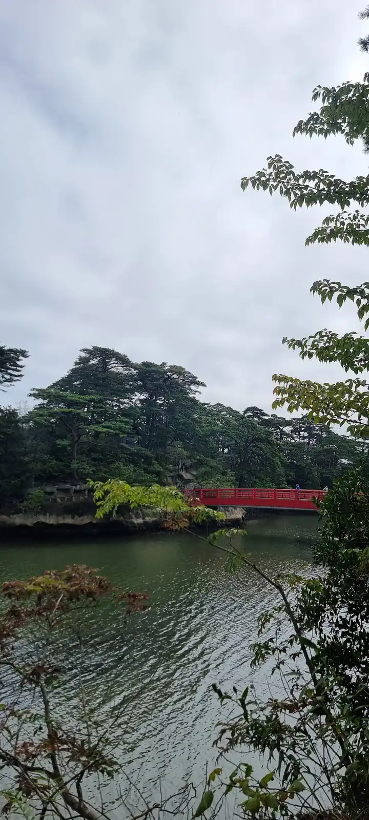 A red arched bridge over a garden pond