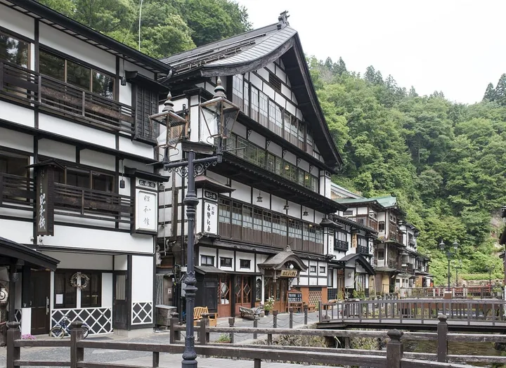 Wooden inns lining a narrow river street in Ginzan Onsen